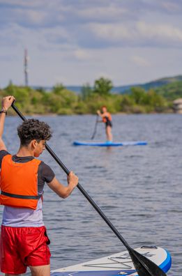 un joven y una chica practicando SUP en el embalse de Pinilla en Lozoya